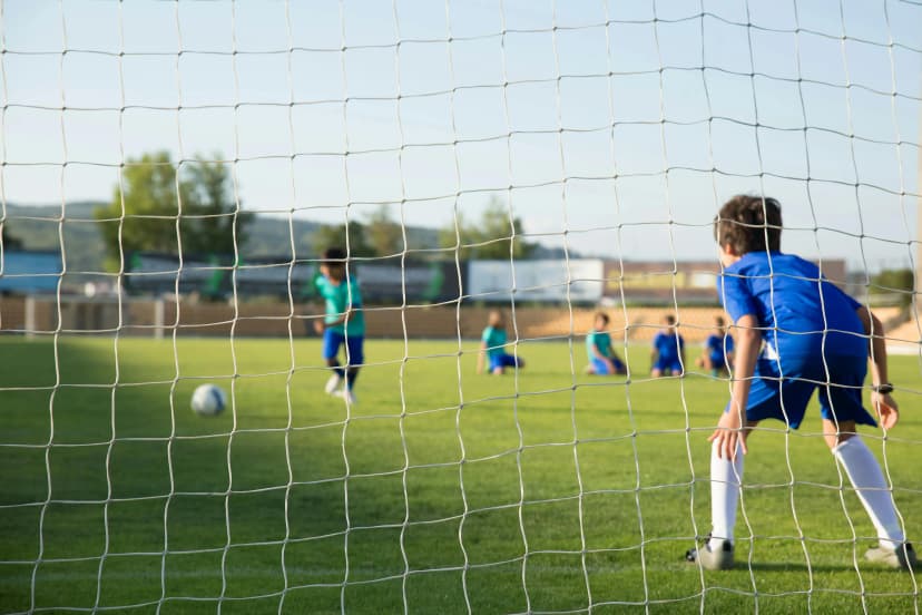 A young boy in a blue uniform acting as a goalkeeper.